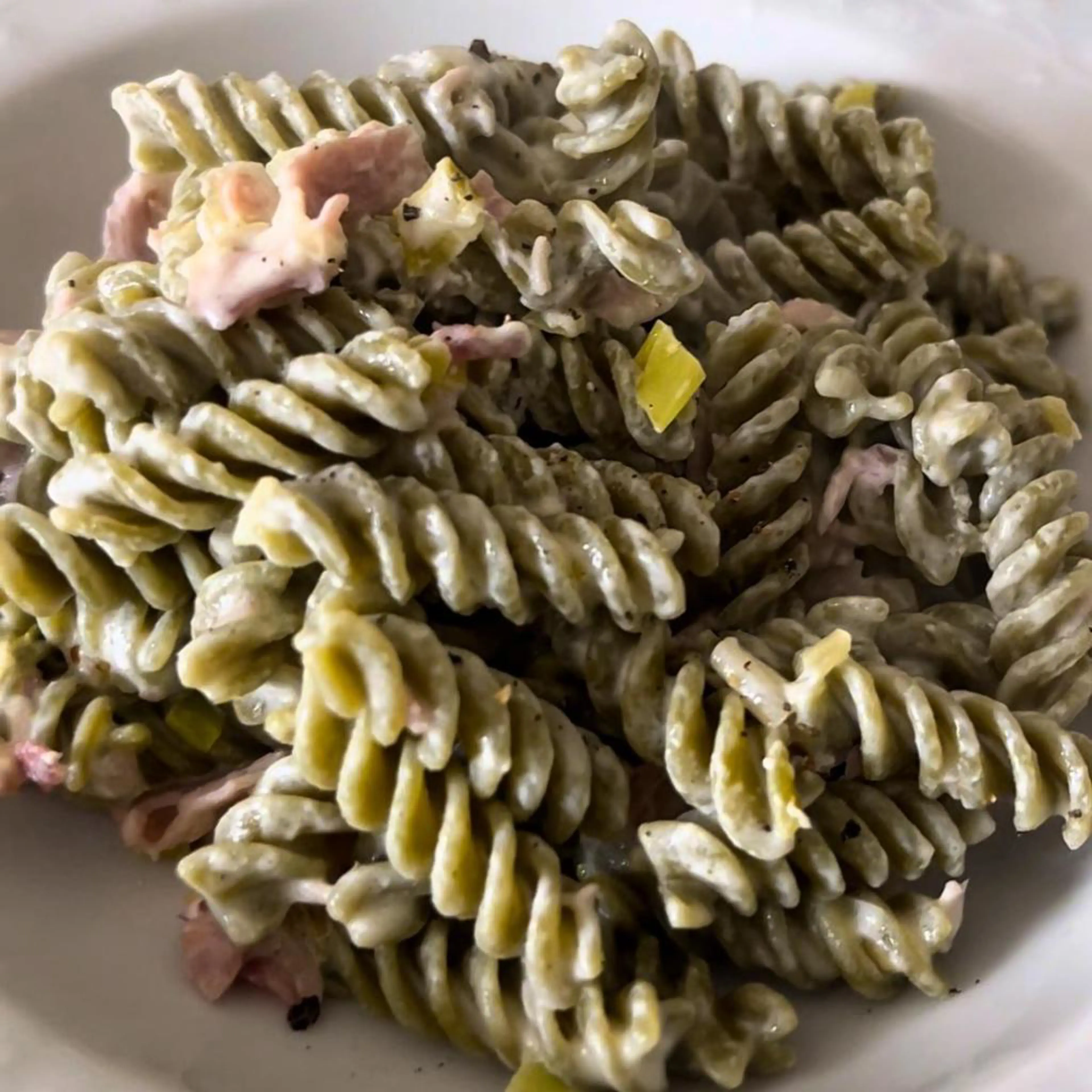 Pea fusilli with a creamy spreadable cheese and cooked ham sauce